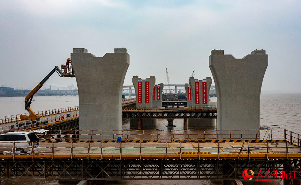 3月12日，在寧波市鎮海區灰鱉洋南岸灘涂之上，工人在棧橋搭建起的海上施工通道上有序施工。人民網 章勇濤攝