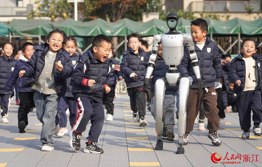 在寧波市江北區慈城懷之幼兒園，孩子們和人形機器人奔跑在校園里。人民網 章勇濤攝